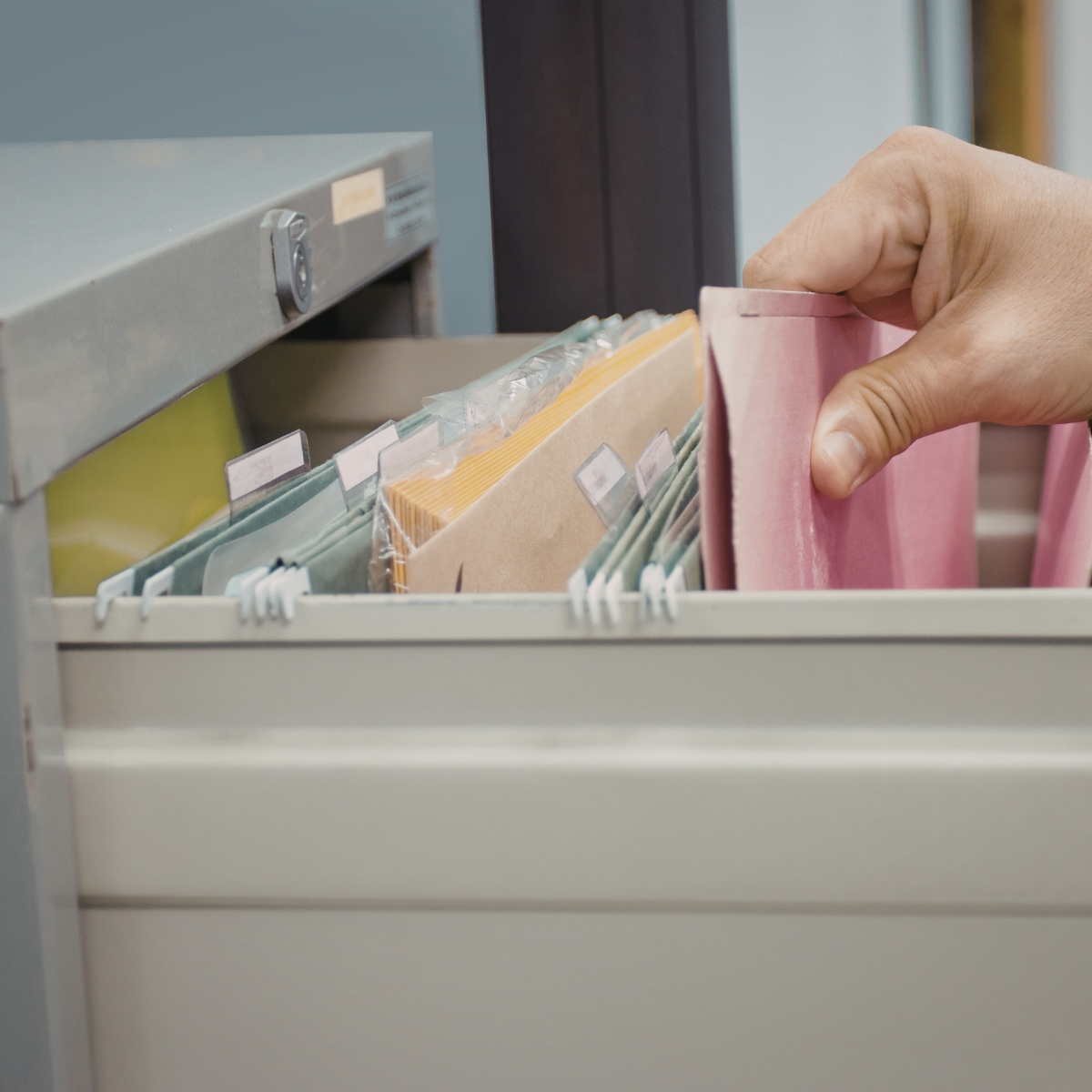 A hand removing a file from a file cabinet